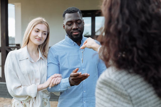 A real estate agent handing keys over to two people
